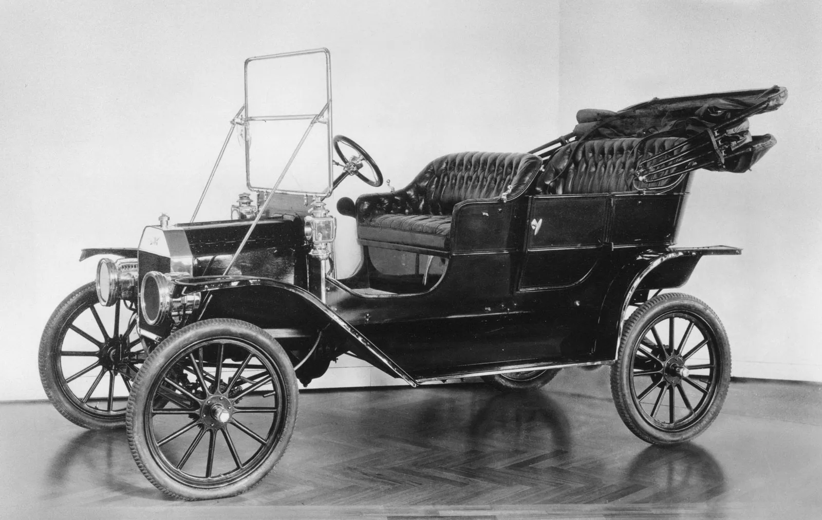1909 black Ford Model T with top down, two rows of seats, running boards, and brass radiator